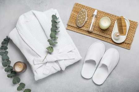 Flat lay composition with bathrobe and spa essentials on light gray background
