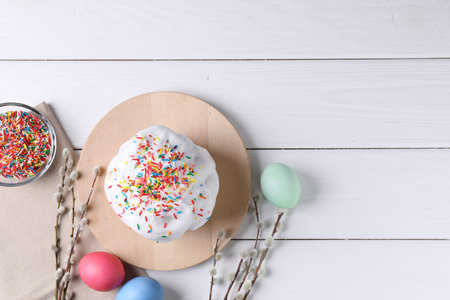 Delicious Easter cake decorated with sprinkles, painted eggs and willow branches on white wooden...