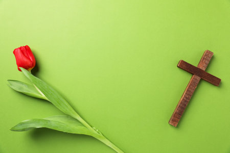 Easter attributes. Wooden cross and beautiful tulip on green background, flat lay. Space for textの写真素材