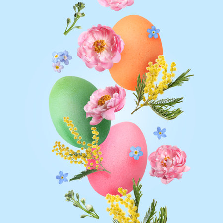 Easter eggs and spring flowers falling against light blue background