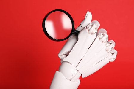 Mannequin hand with magnifying glass on red background, closeupの写真素材