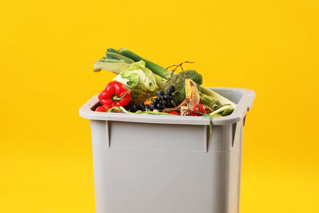 Garbage in trash bin on orange background, space for text. Waste sortingの写真素材