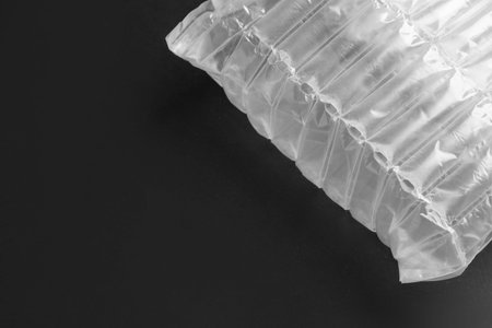 Transparent air buffer packaging on black background, top view. Space for text