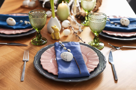 Easter celebration. Festive table setting with flowers and painted eggs indoors, closeup
