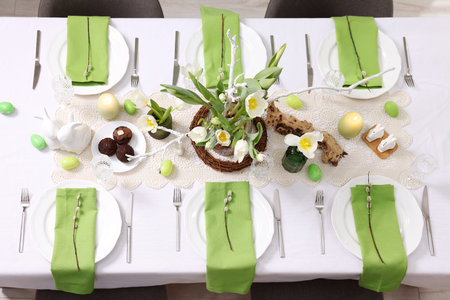 Easter celebration. Festive table setting with elegant dishware and flowers, top view