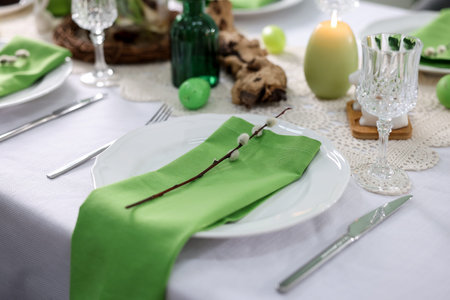 Easter celebration. Festive table setting with elegant dishware and willow branches, closeup