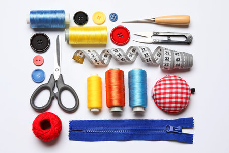 Different sewing supplies on white background, flat lay