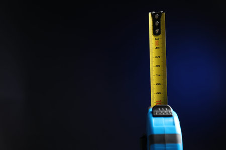 Measuring tape on black background, closeup. Space for text