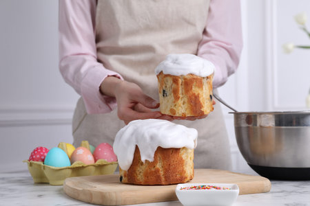 Woman with traditional Easter cakes at white marble table indoors, closeup