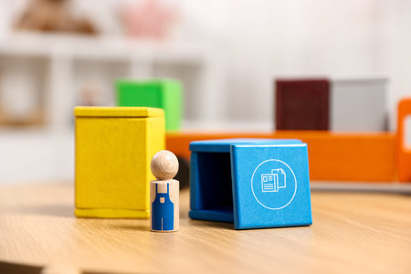 Garbage sorting play set for children. Bright trash bins and human figure on wooden table indoors,...