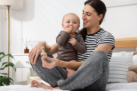 Mother with her cute baby on bed at home