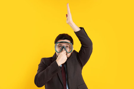 Office worker with diving mask on orange backgroundの写真素材