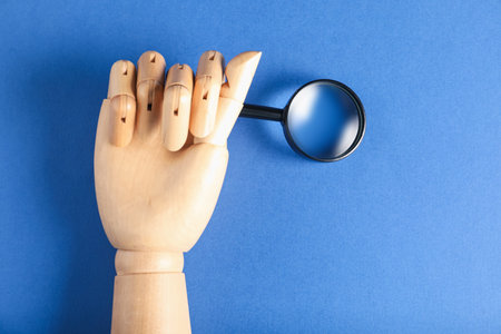 Mannequin hand with magnifying glass on blue background, closeupの写真素材