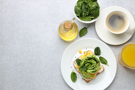 Tasty breakfast with avocado toast served on light gray table, flat lay. Space for text