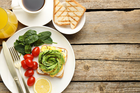 Tasty breakfast with avocado toast served on wooden table, flat lay. Space for text