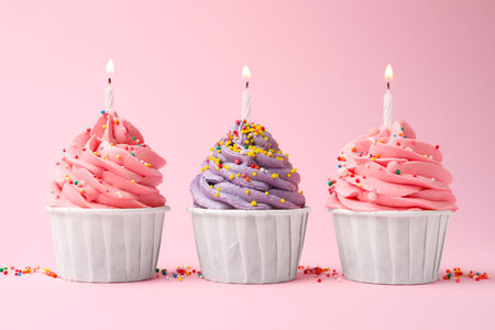 Yummy cupcakes with sprinkles and candles on pink backgroundの写真素材