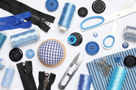 Different sewing supplies on white background, flat lay