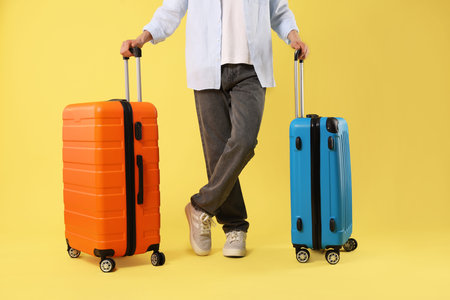 Man with suitcases on yellow background, closeupの写真素材