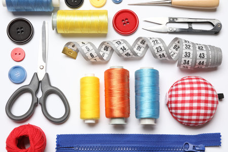 Different sewing supplies on white background, flat lay