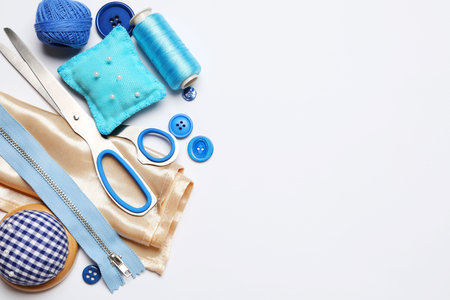 Different sewing supplies on white background, flat lay. Space for text
