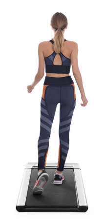 Sporty woman using walking treadmill on white background, back view