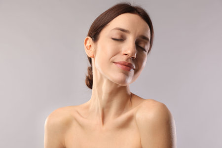 Portrait of beautiful woman with healthy skin on light gray background
