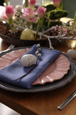 Easter celebration. Festive table setting with flowers and painted eggs indoors, closeup