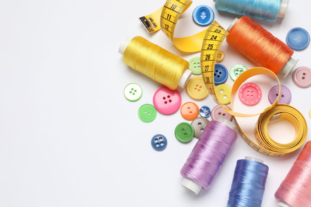 Flat lay composition with sewing supplies on white background. Space for text