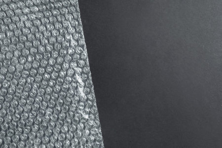 Transparent bubble wrap on black background, top view. Space for text