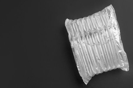 Transparent air buffer packaging on black background, top view. Space for text