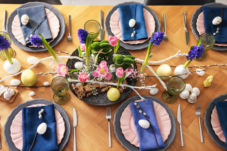 Easter celebration. Festive table setting with flowers and painted eggs indoors, flat lay