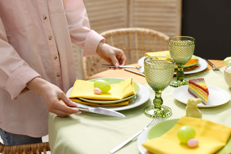Woman setting festive table for Easter celebration at home, closeup