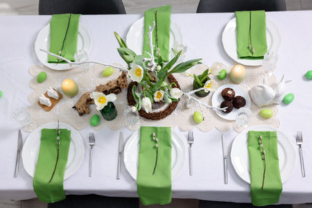Easter celebration. Festive table setting with elegant dishware and flowers, top view