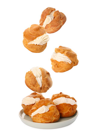 Profiteroles with cream falling onto plate against white background