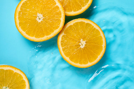 Orange slices in water on light blue background, flat lay