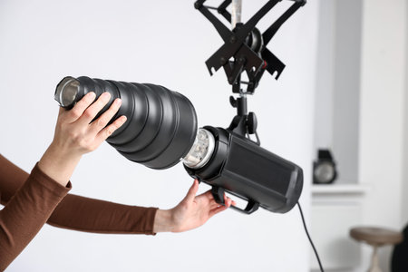 Woman with professional lighting equipment in photo studio, closeup