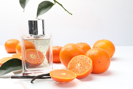 Bottle of perfume, tangerines and vanilla pods on white background, closeup. Space for text