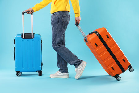 Man with suitcases on light blue background, closeup