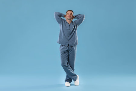 Man in stylish pajamas on light blue backgroundの写真素材