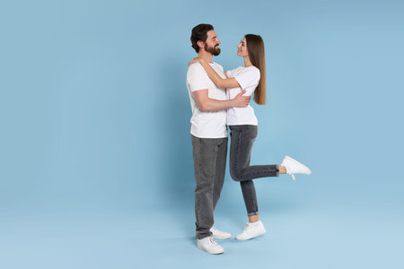 Romantic date. Portrait of lovely couple on light blue background, space for textの写真素材