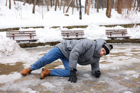 Young man fallen on slippery pathway covered in ice outdoorsの写真素材