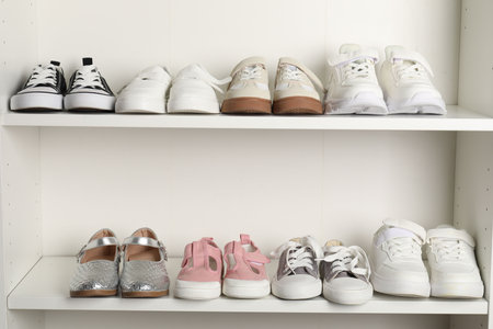 Different stylish children's shoes on shelving unit indoors, closeupの写真素材