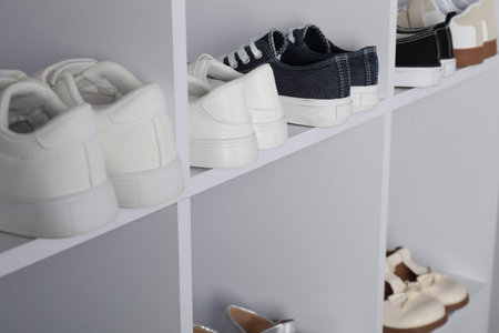 Different stylish children's shoes on shelving unit indoors, closeupの写真素材
