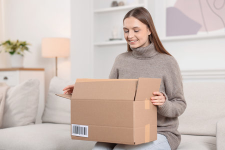 Woman with parcel on sofa at home. Space for text