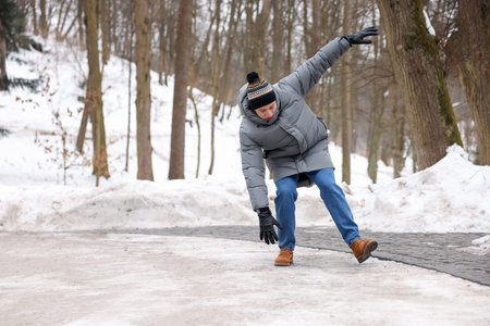 Young man falling on slippery pathway covered in ice outdoors, space for textの写真素材