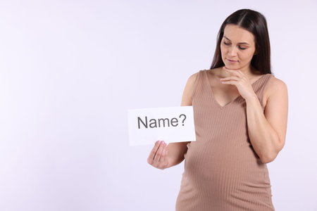 Pregnant woman holding card with word Name and question mark on white background, space for textの写真素材