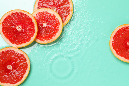 Slices of grapefruit in water on turquoise background, flat lay. Space for textの写真素材