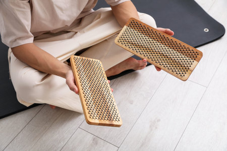 Young man with sadhu boards sitting on yoga mat at home, closeupの写真素材