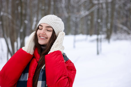Portrait of beautiful woman in snowy forest. Space for text