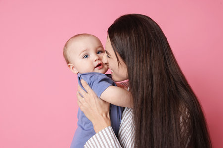 Happy mother with her cute baby on pink backgroundの写真素材